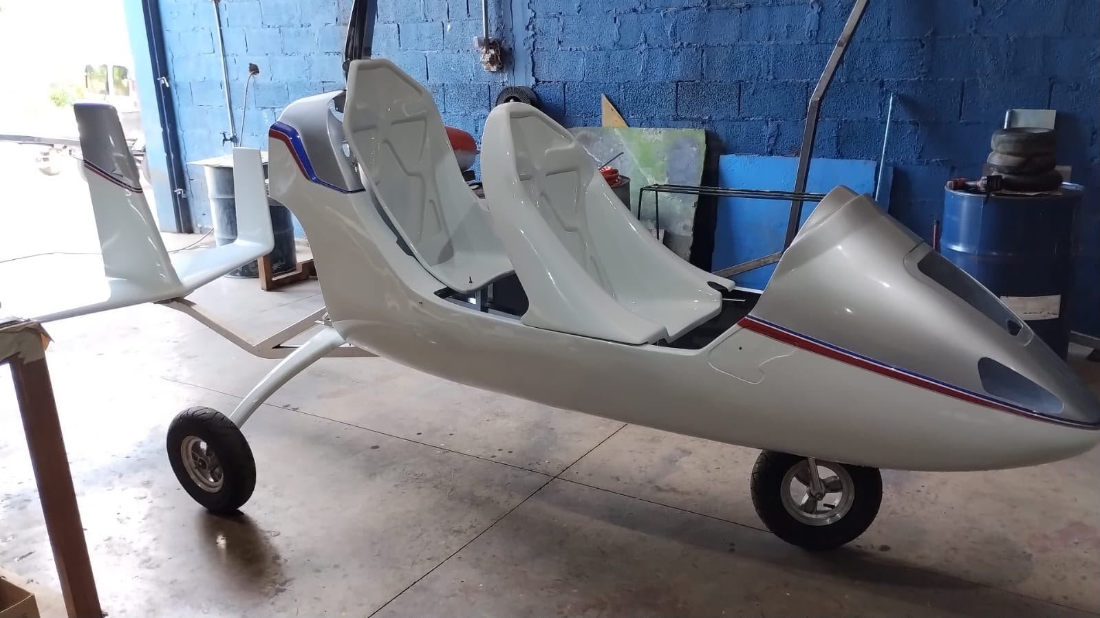 Girocóptero branco completo na oficina, visto de lado, com assentos e empenagem instalados