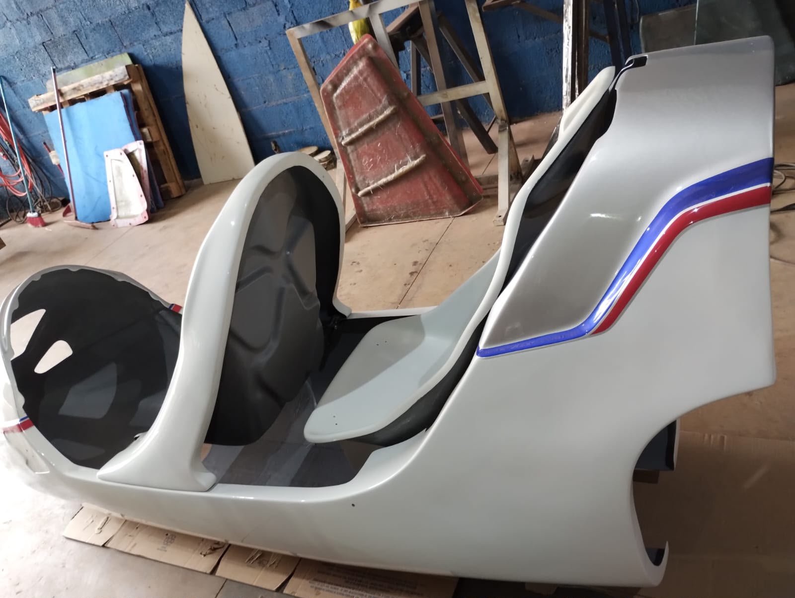 Casco de girocóptero branco com faixa azul e vermelha em fase de acabamento